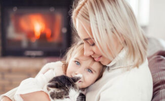 Image of a mother, daughter, and cat near a fireplace