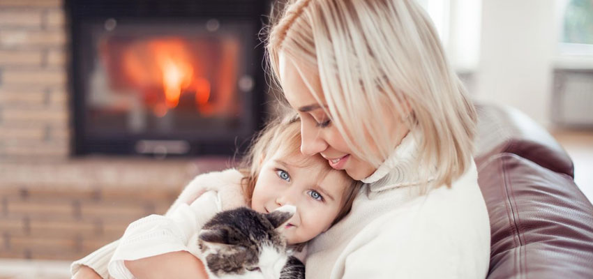 Image of a mother, daughter, and cat near a fireplace