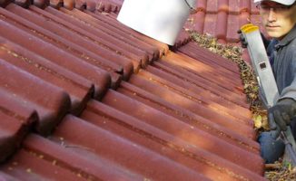 homeowner clearing gutters as part of spring home maintenance work