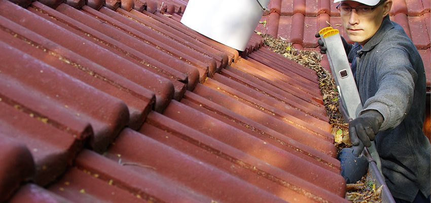 homeowner clearing gutters as part of spring home maintenance work