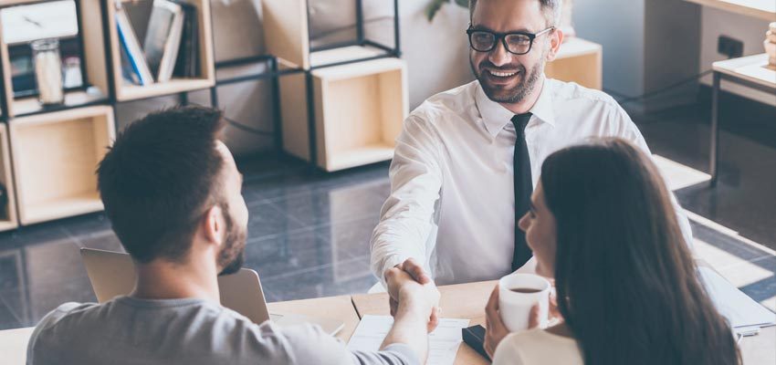 Couple meeting with their insurance agent shaking hands