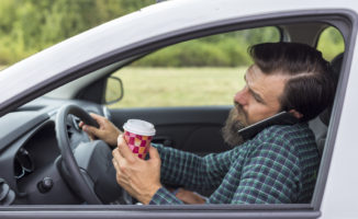 driving holding coffee and talking on the phone