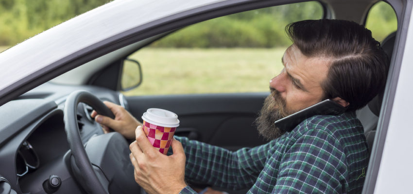 driving holding coffee and talking on the phone