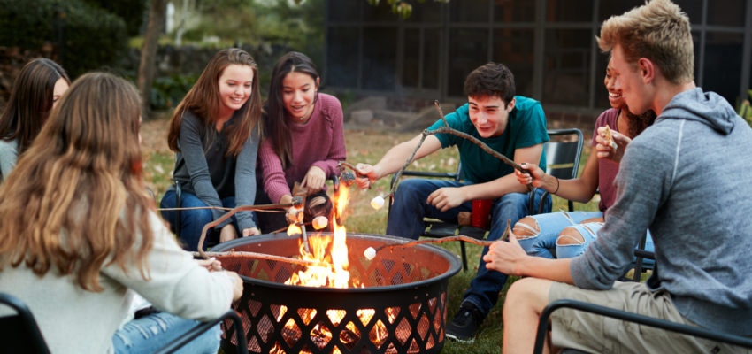 Group of friends making smores by fire pit